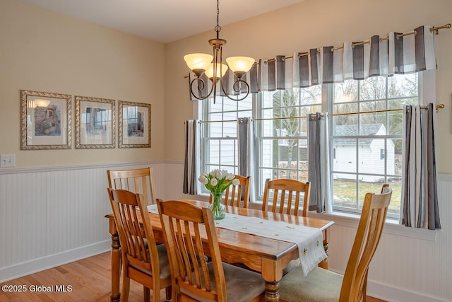 dining room featuring an inviting chandelier, wood finished floors, and wainscoting