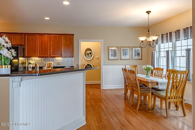 dining area with recessed lighting, light wood-type flooring, and an inviting chandelier