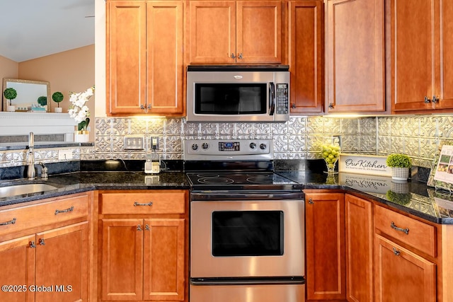 kitchen with a sink, stainless steel appliances, decorative backsplash, and dark stone counters