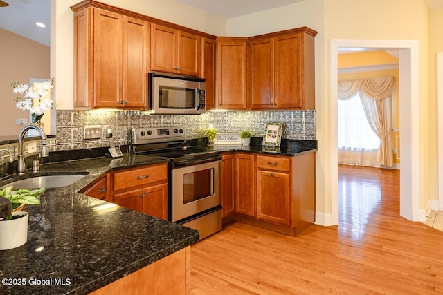 kitchen with decorative backsplash, light wood-style flooring, appliances with stainless steel finishes, and a sink