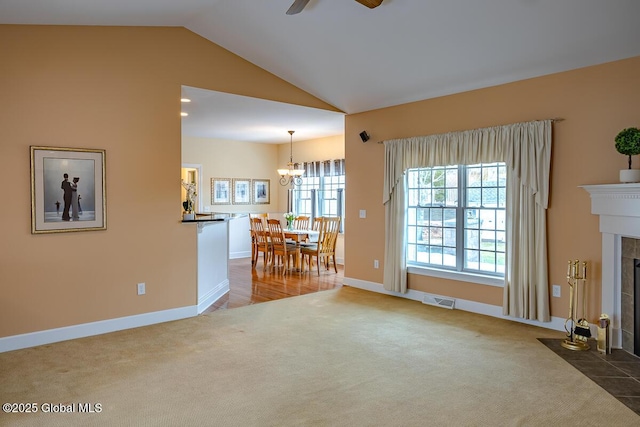 unfurnished living room with visible vents, ceiling fan with notable chandelier, a fireplace, carpet flooring, and lofted ceiling