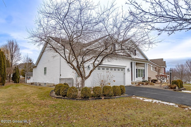 view of side of property featuring aphalt driveway, an attached garage, and a lawn