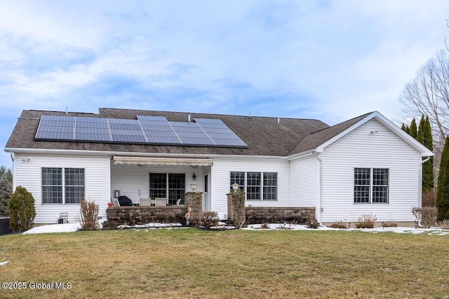 rear view of property featuring solar panels, central air condition unit, a yard, and a shingled roof