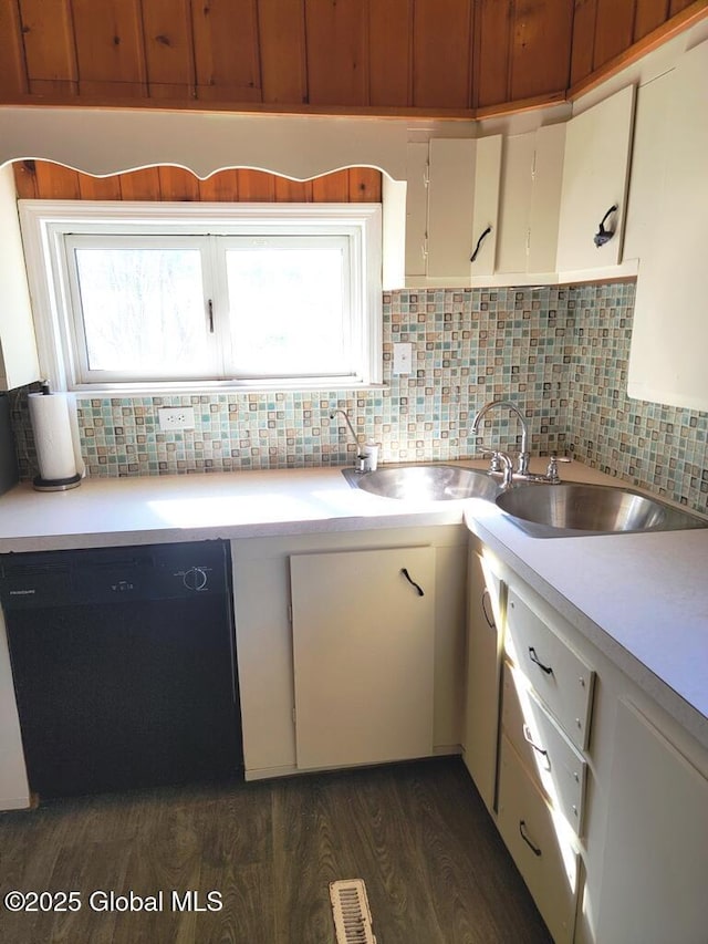 kitchen with tasteful backsplash, light countertops, dishwasher, and dark wood-type flooring