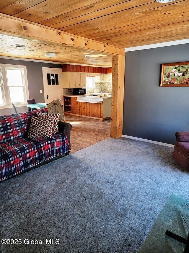 living area with wood ceiling, light colored carpet, and baseboards