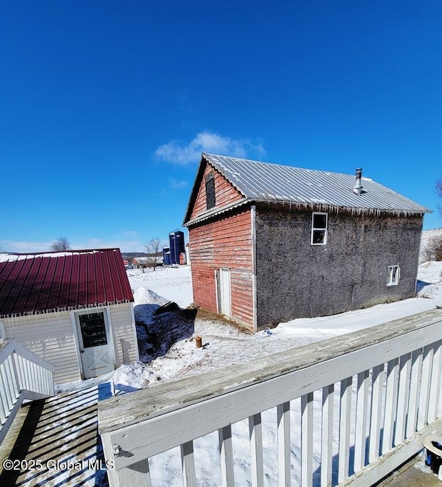 snow covered property featuring an outbuilding and metal roof