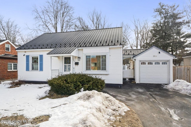 view of front of house featuring driveway, fence, and metal roof