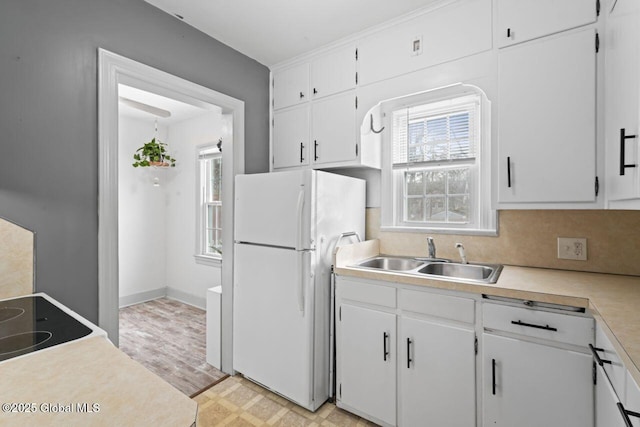 kitchen with light countertops, a wealth of natural light, a sink, and freestanding refrigerator