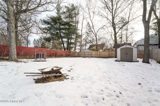 yard layered in snow with an outbuilding, a shed, and a fenced backyard