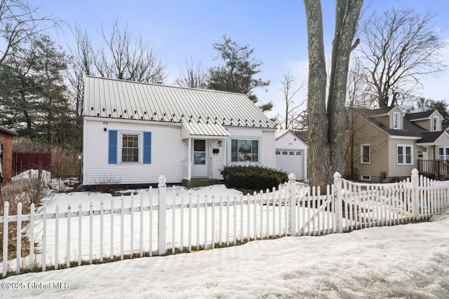 view of front of home with a garage, a standing seam roof, a fenced front yard, and metal roof