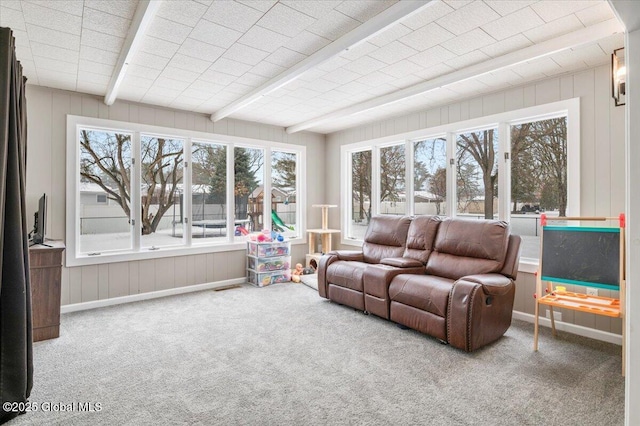 carpeted living area featuring beamed ceiling and baseboards