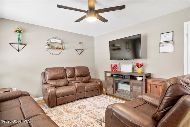 living area with a ceiling fan, light wood-style floors, and baseboards