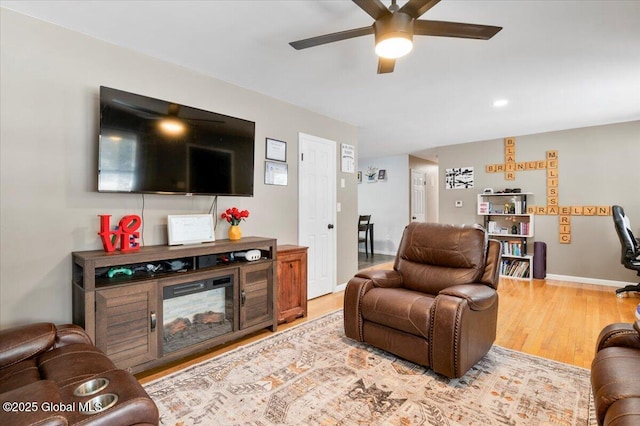 living area featuring wood finished floors, a ceiling fan, and baseboards