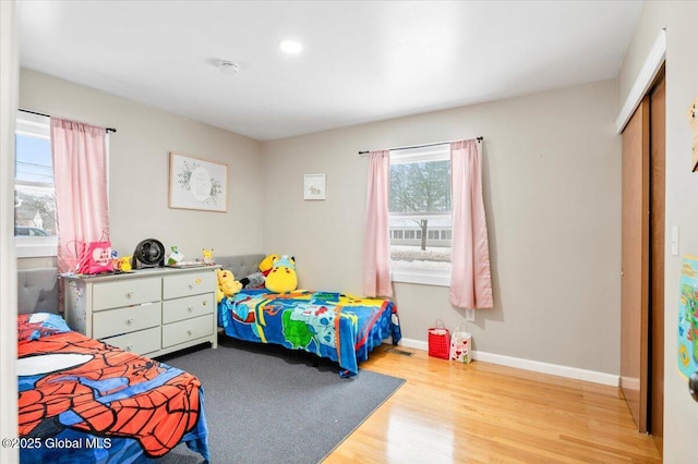 bedroom with a closet, wood finished floors, and baseboards