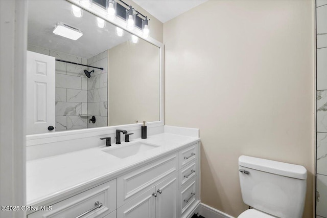 bathroom with tiled shower, vanity, and toilet