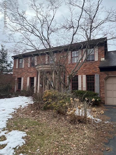 colonial home featuring a garage, brick siding, and driveway