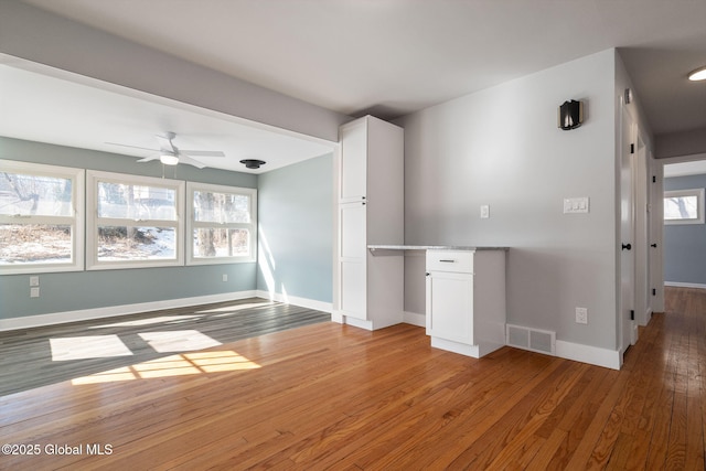 unfurnished room featuring light wood-style flooring, plenty of natural light, visible vents, and baseboards