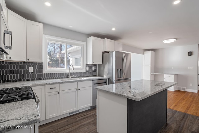 kitchen with dark wood-type flooring, a sink, visible vents, appliances with stainless steel finishes, and backsplash