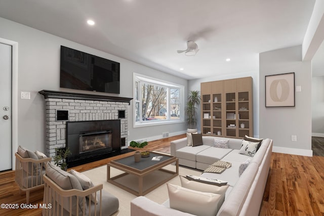 living area with recessed lighting, a fireplace, wood finished floors, visible vents, and baseboards