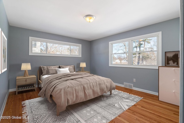 bedroom featuring visible vents, baseboards, and wood finished floors