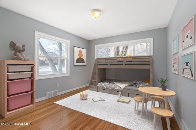 bedroom featuring baseboards, visible vents, and wood finished floors