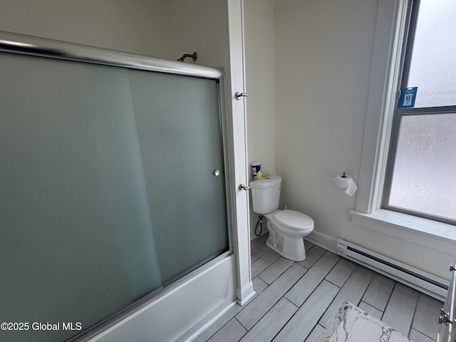 bathroom featuring wood finish floors, toilet, baseboards, a baseboard radiator, and enclosed tub / shower combo