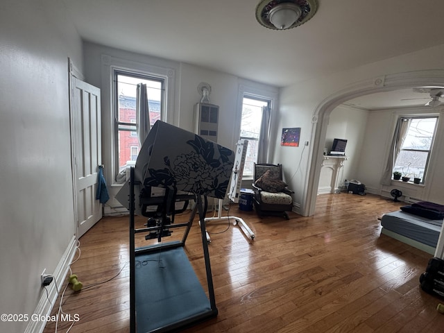 workout room with arched walkways, a healthy amount of sunlight, and hardwood / wood-style flooring