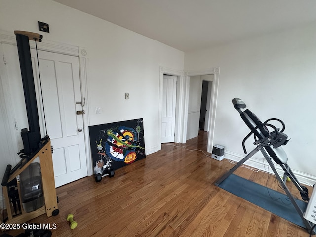 workout area with baseboards and wood finished floors