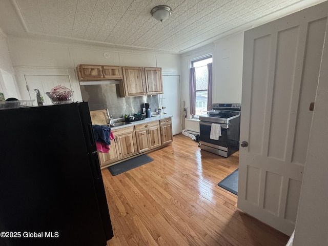 kitchen with light wood-type flooring, an ornate ceiling, stainless steel range with electric cooktop, freestanding refrigerator, and light countertops