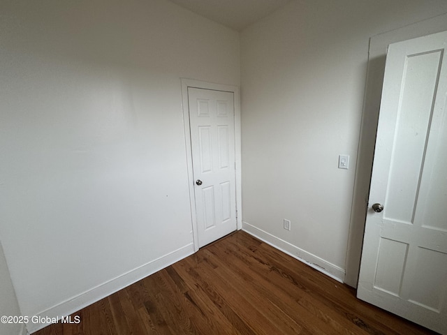 empty room featuring dark wood-type flooring and baseboards