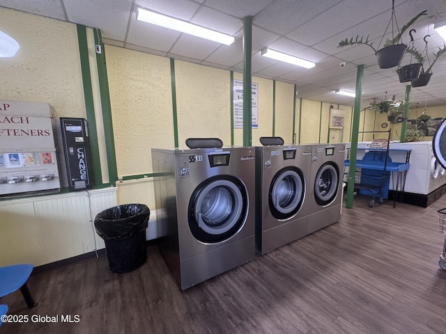 community laundry room featuring washing machine and dryer, a textured wall, and wood finished floors