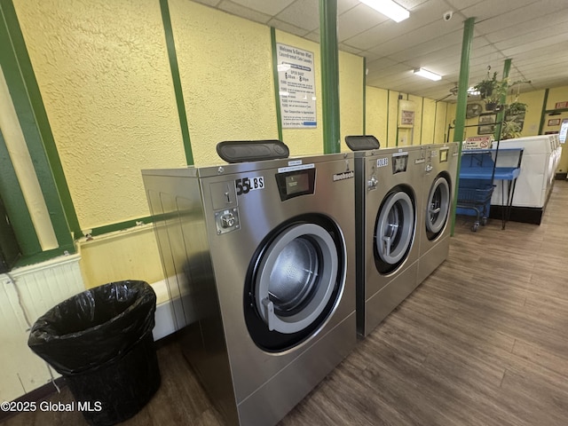 shared laundry area with wainscoting, independent washer and dryer, a textured wall, and wood finished floors