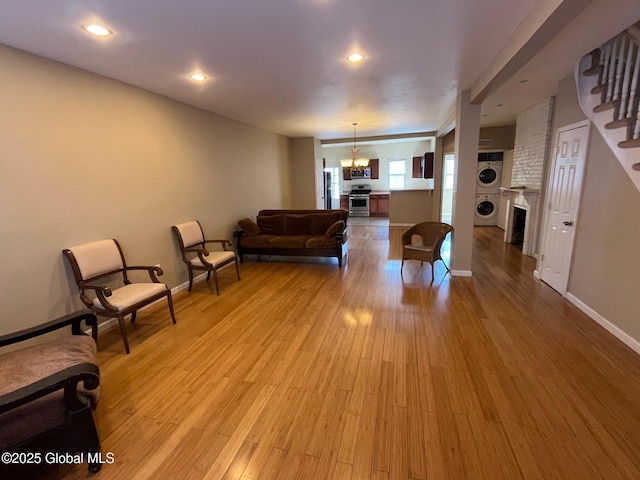 living room featuring stairway, stacked washer / dryer, a fireplace, and light wood-style floors