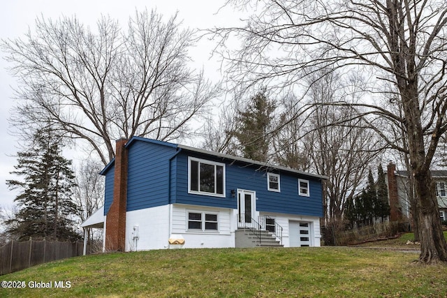 view of front of house with entry steps, a chimney, a front yard, and fence