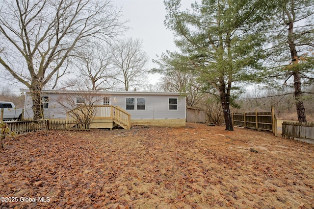 rear view of house with a deck, fence, and crawl space