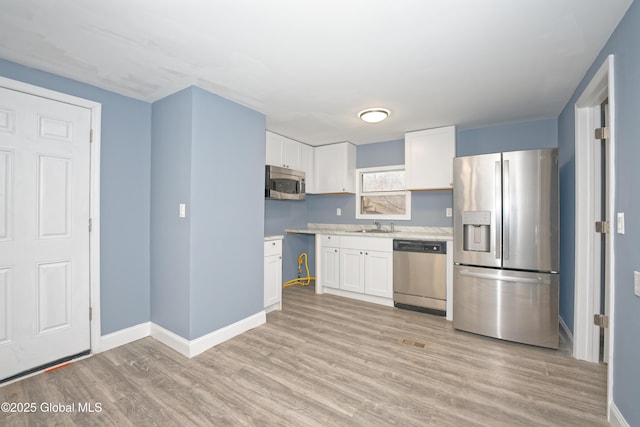 kitchen featuring white cabinetry, light wood-style flooring, a sink, and stainless steel appliances