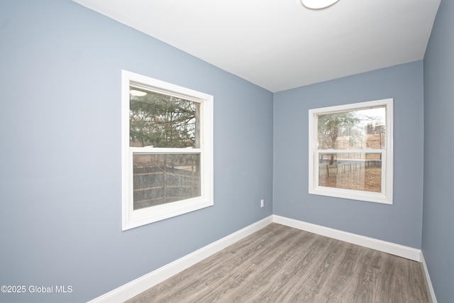 spare room featuring baseboards and wood finished floors