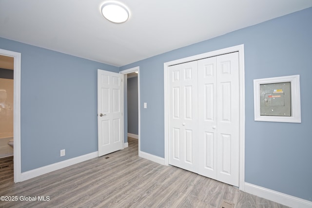 unfurnished bedroom featuring a closet, baseboards, and wood finished floors