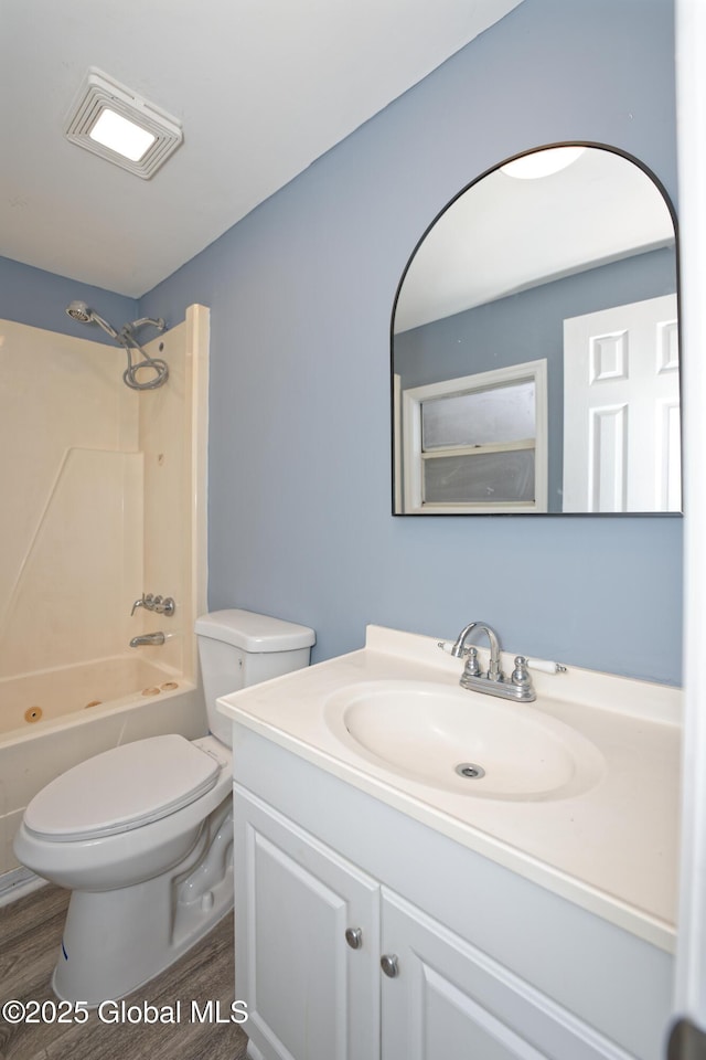 bathroom with vanity, toilet, wood finished floors, and bathtub / shower combination