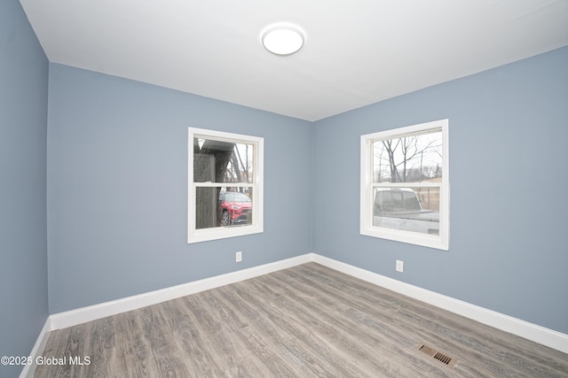 empty room with visible vents, baseboards, and wood finished floors