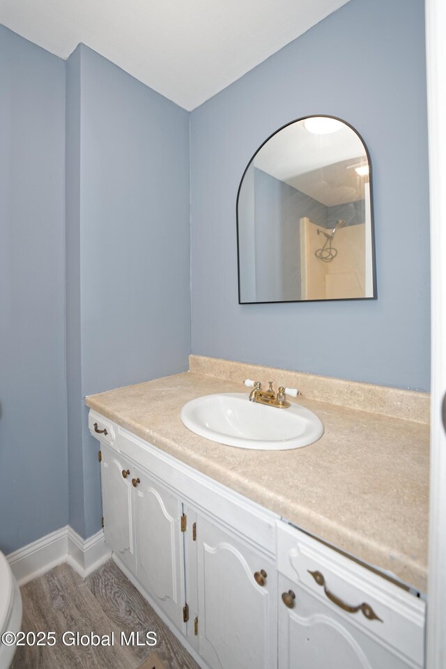 bathroom with baseboards, toilet, wood finished floors, and vanity