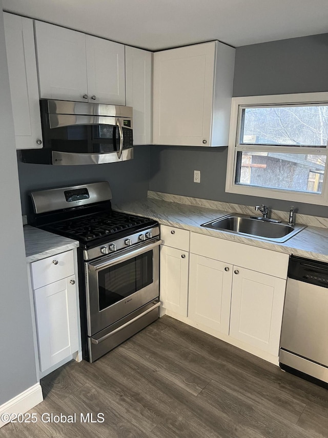 kitchen with dark wood-style floors, white cabinets, stainless steel appliances, and a sink