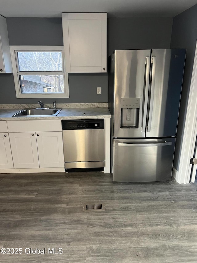 kitchen with visible vents, appliances with stainless steel finishes, wood finished floors, white cabinets, and a sink