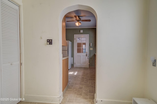 hall featuring baseboards and arched walkways