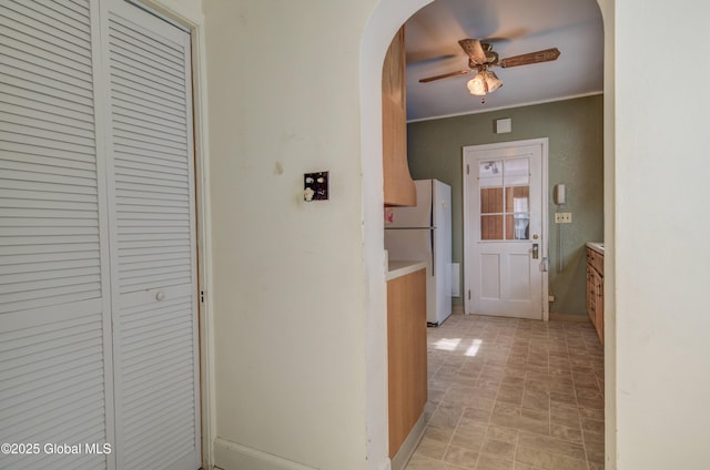 hallway featuring arched walkways, baseboards, and ornamental molding