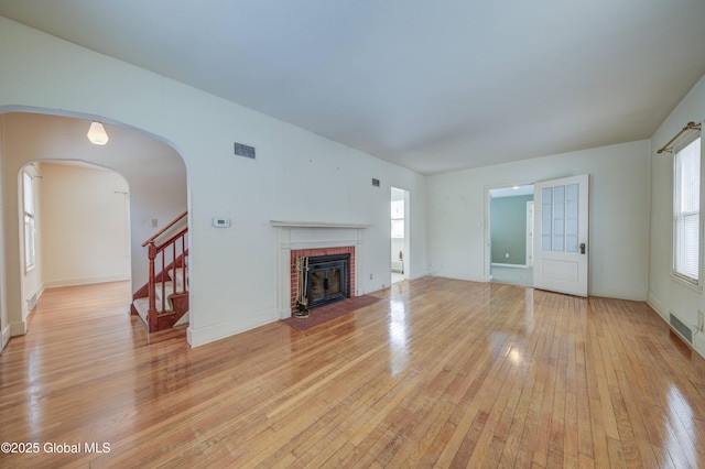 unfurnished living room with visible vents, light wood-style flooring, a fireplace, and plenty of natural light