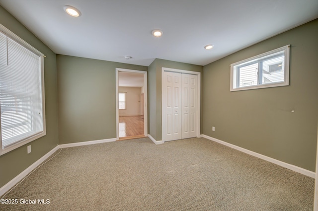 unfurnished bedroom featuring a closet, recessed lighting, baseboards, and carpet floors