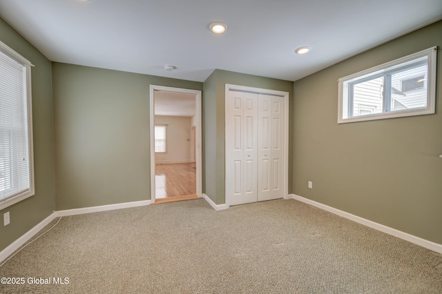 unfurnished bedroom with multiple windows, baseboards, and carpet