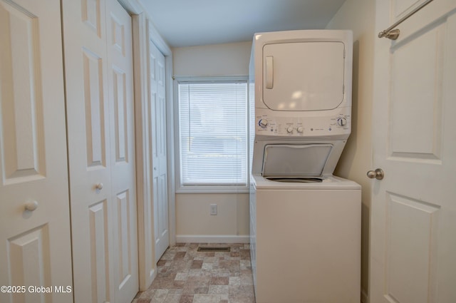 clothes washing area with visible vents, baseboards, laundry area, stacked washer and dryer, and stone finish floor