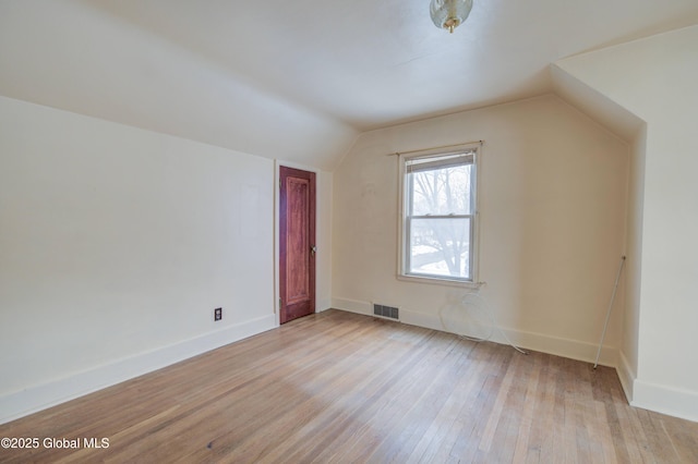 additional living space featuring baseboards, lofted ceiling, visible vents, and light wood finished floors